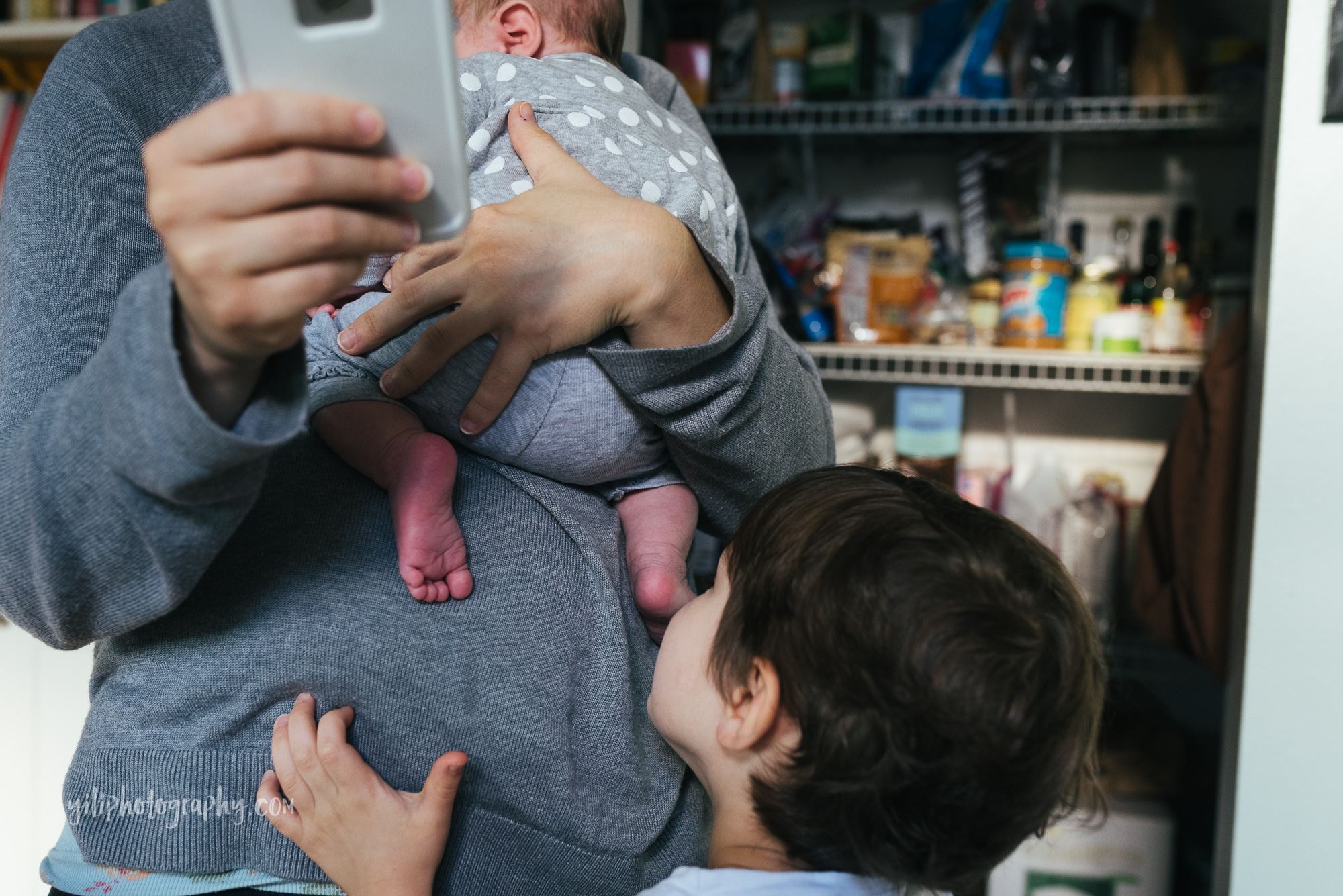 seattle mom checking smartphone while holding newborn girl