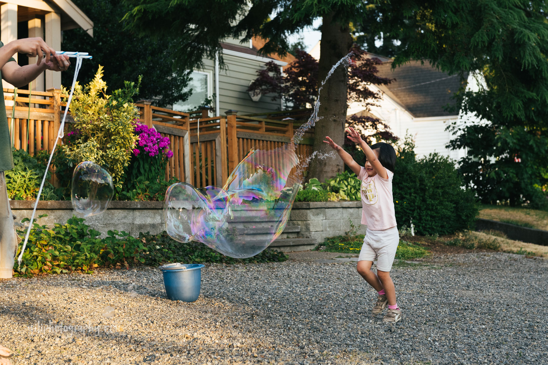 little girl with arms in air popping giant bubble