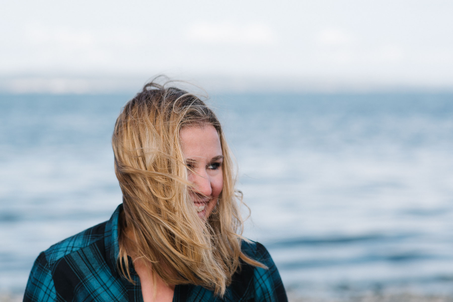 Portrait of caucasian woman with long blonde hair blowing in face at beach