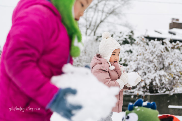 seattle little girl holding snowball with big sister in foreground