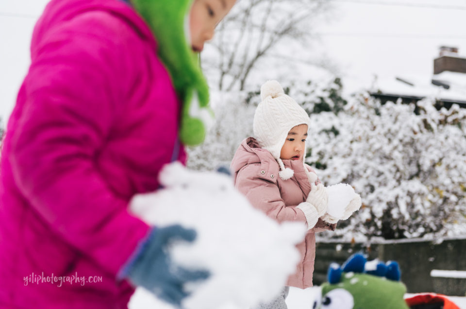 seattle little girl holding snowball with big sister in foreground