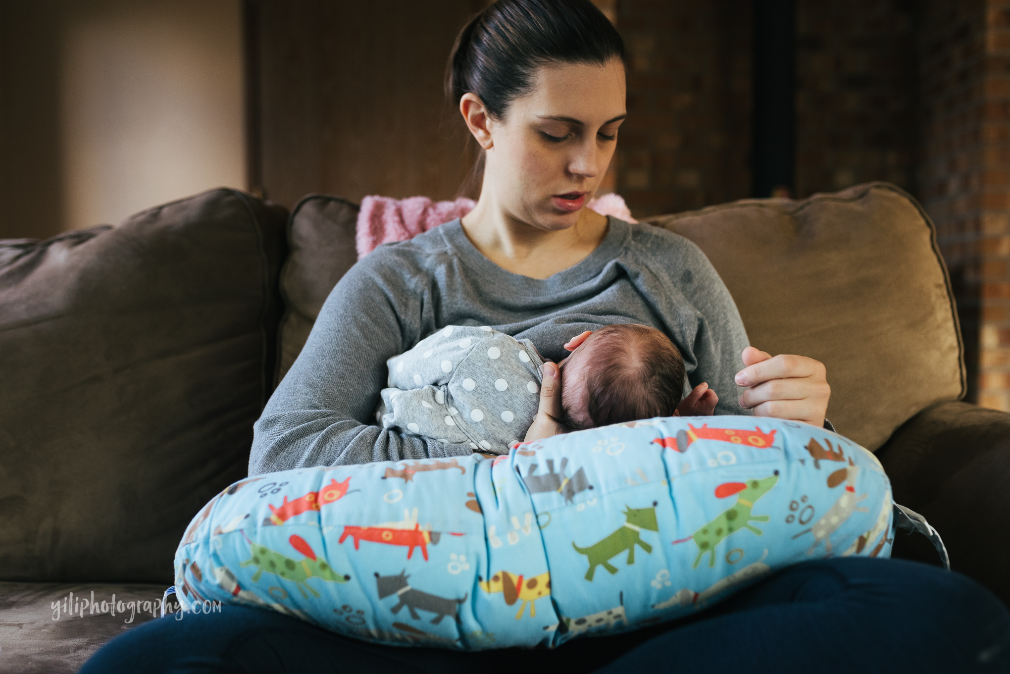 seattle mom sitting on couch nursing newborn baby