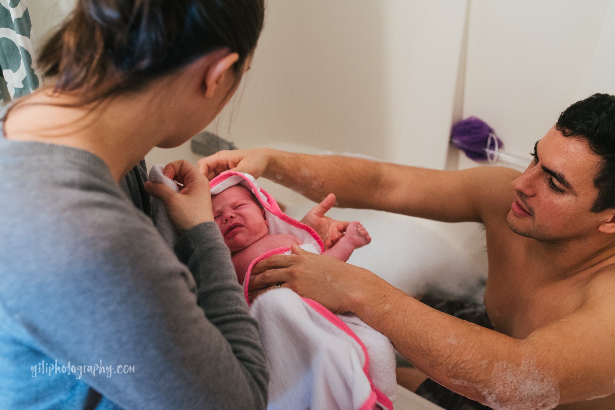 seattle dad handing baby to mom from bathtub