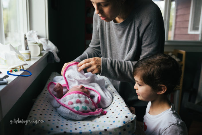 seattle mother drying newborn baby while big brother watches