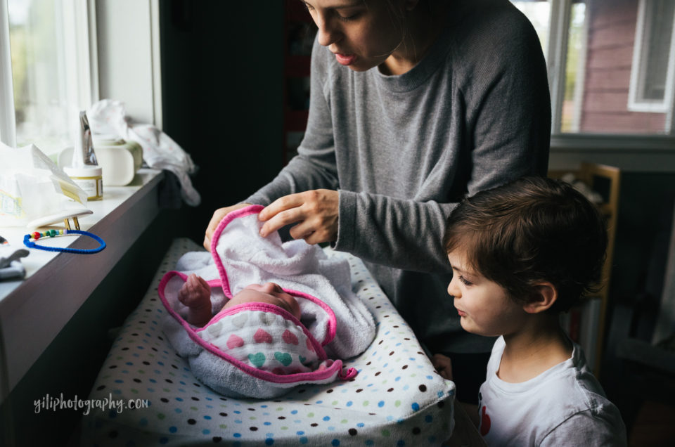 seattle mother drying newborn baby while big brother watches