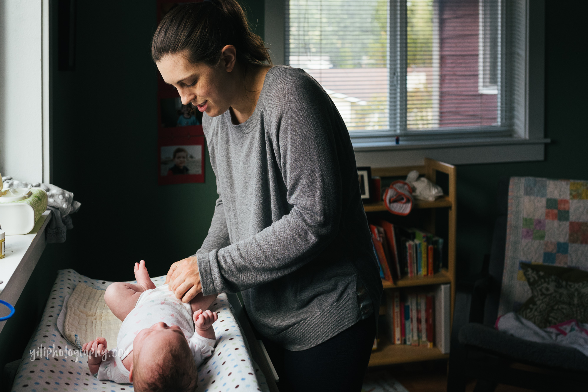 seattle mom smiling while she changes baby