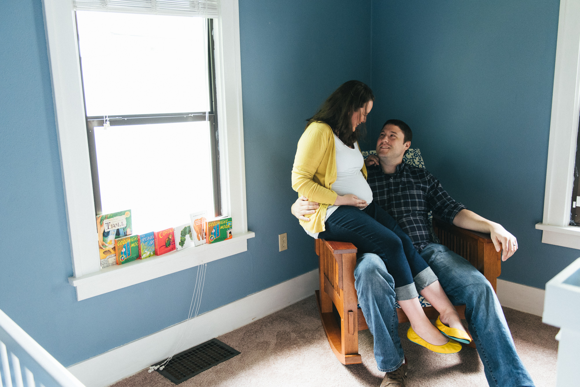 Expecting couple sitting together in baby nursery