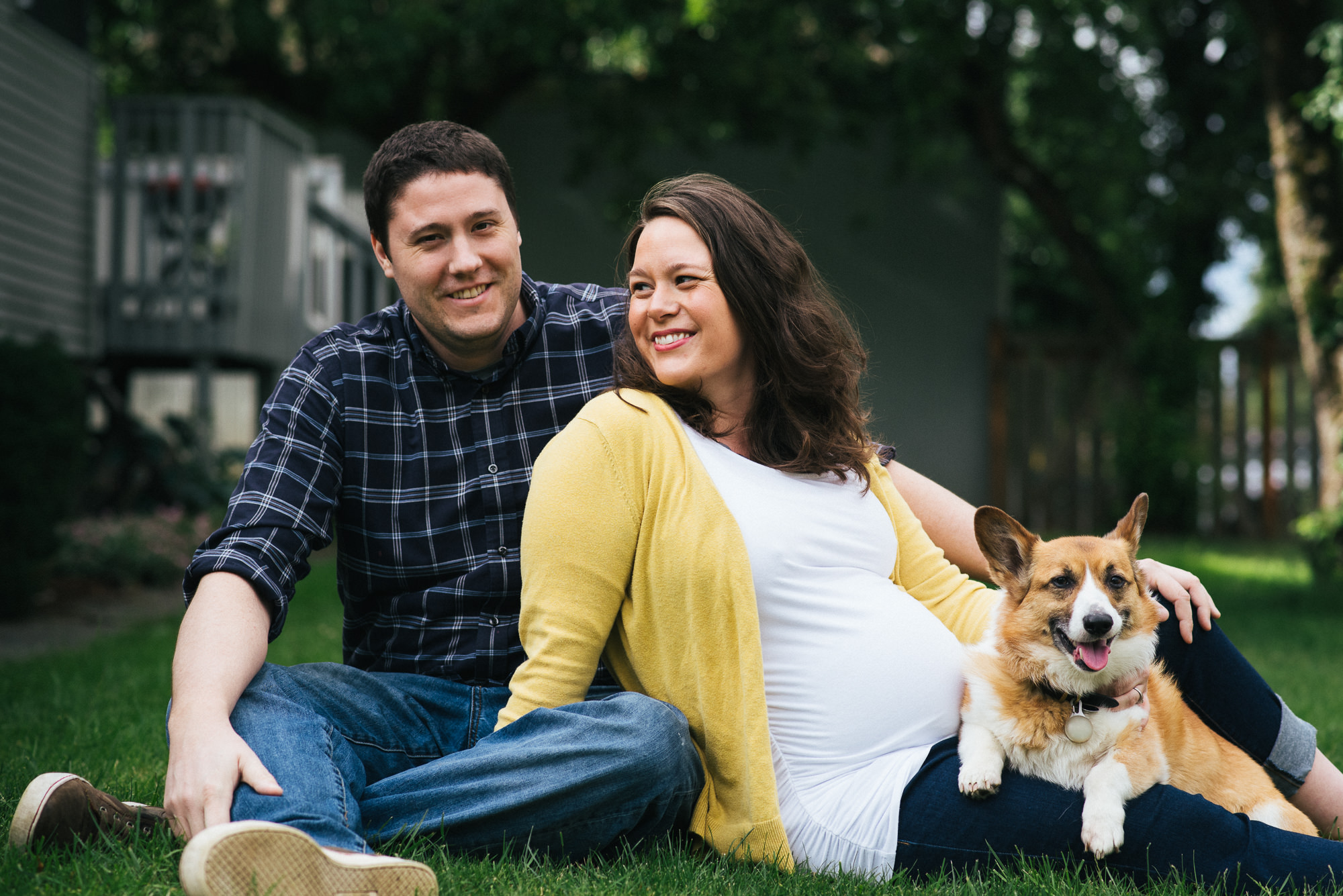 expecting couple sitting in yard with dog