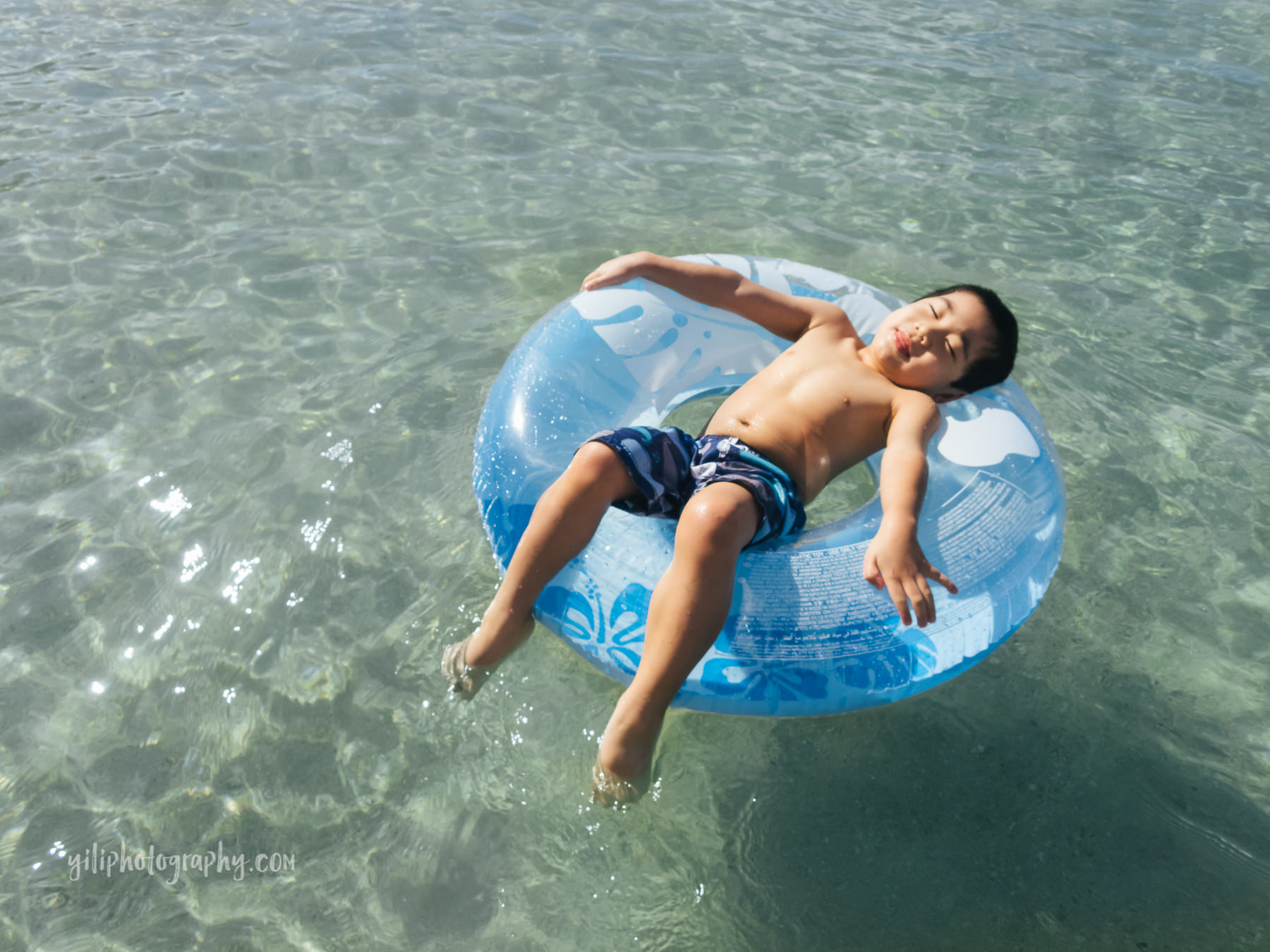 little boy floating in inner tube at beach