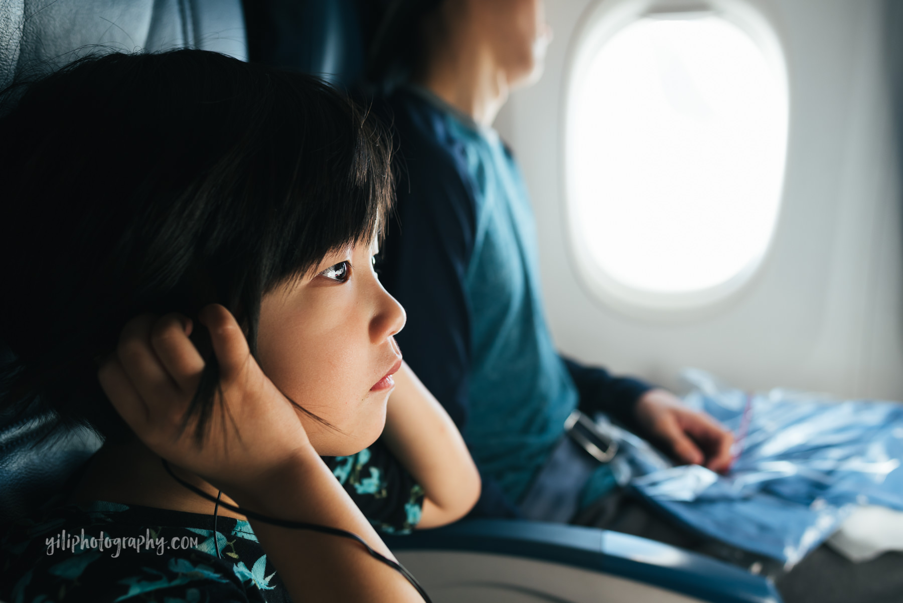 little girl on airplane holding headphones