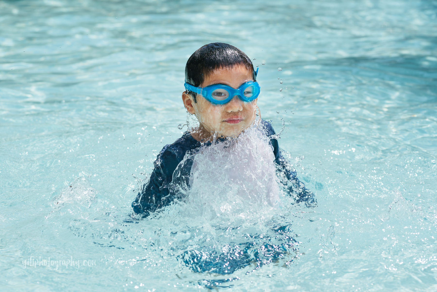 boy with water dripping off face in pool