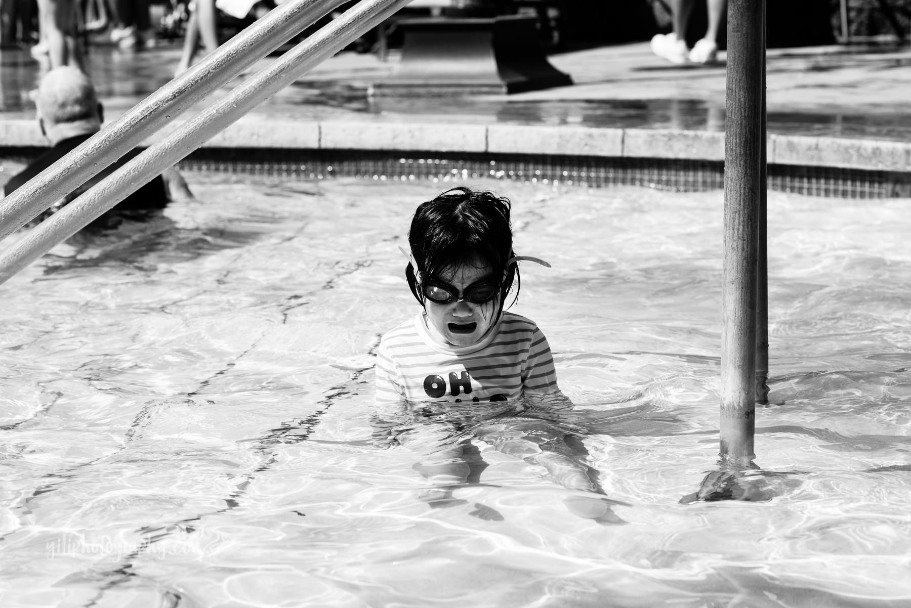 black and white photo of toddler girl having tantrum in pool