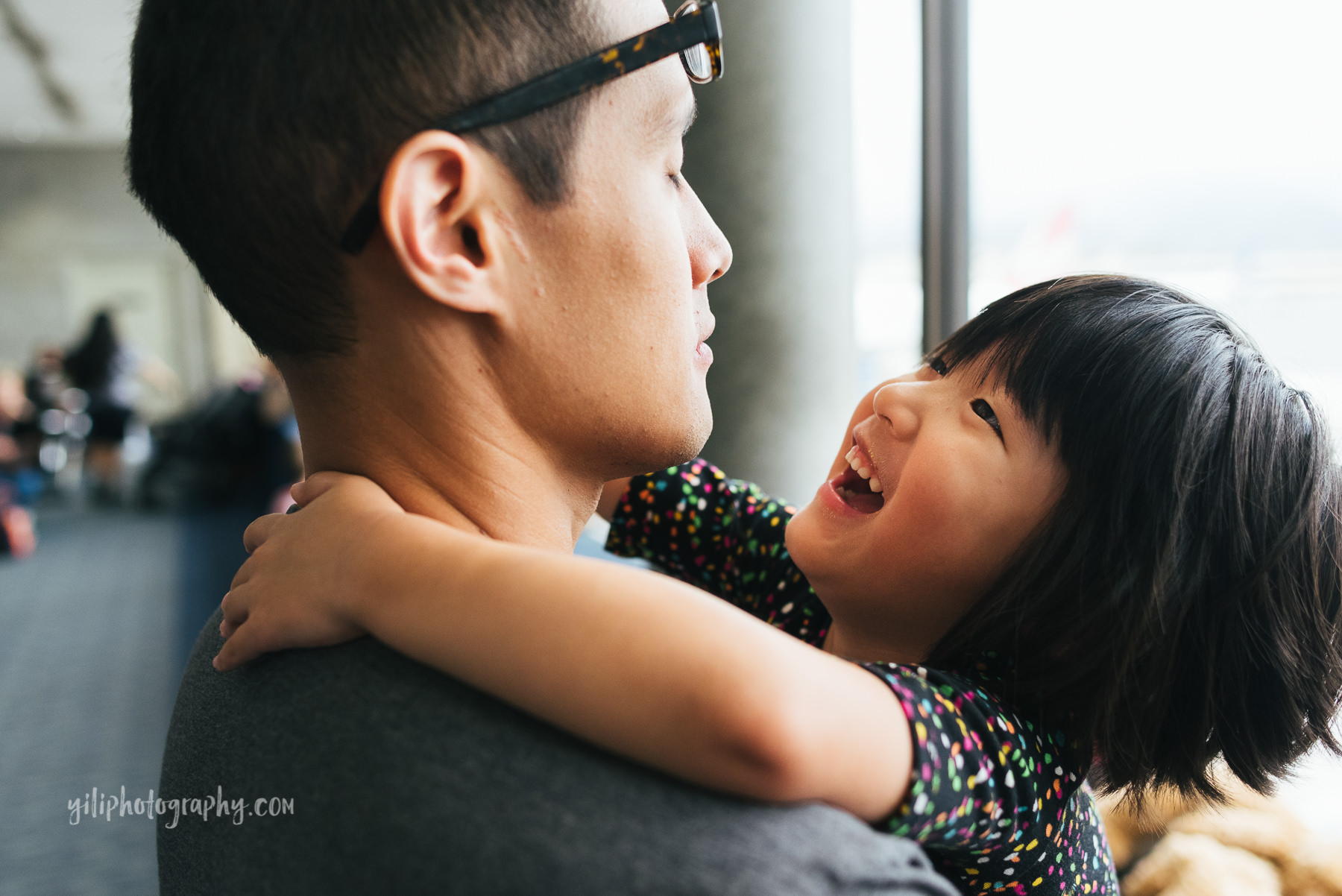 little girl with arms around dads neck laughing