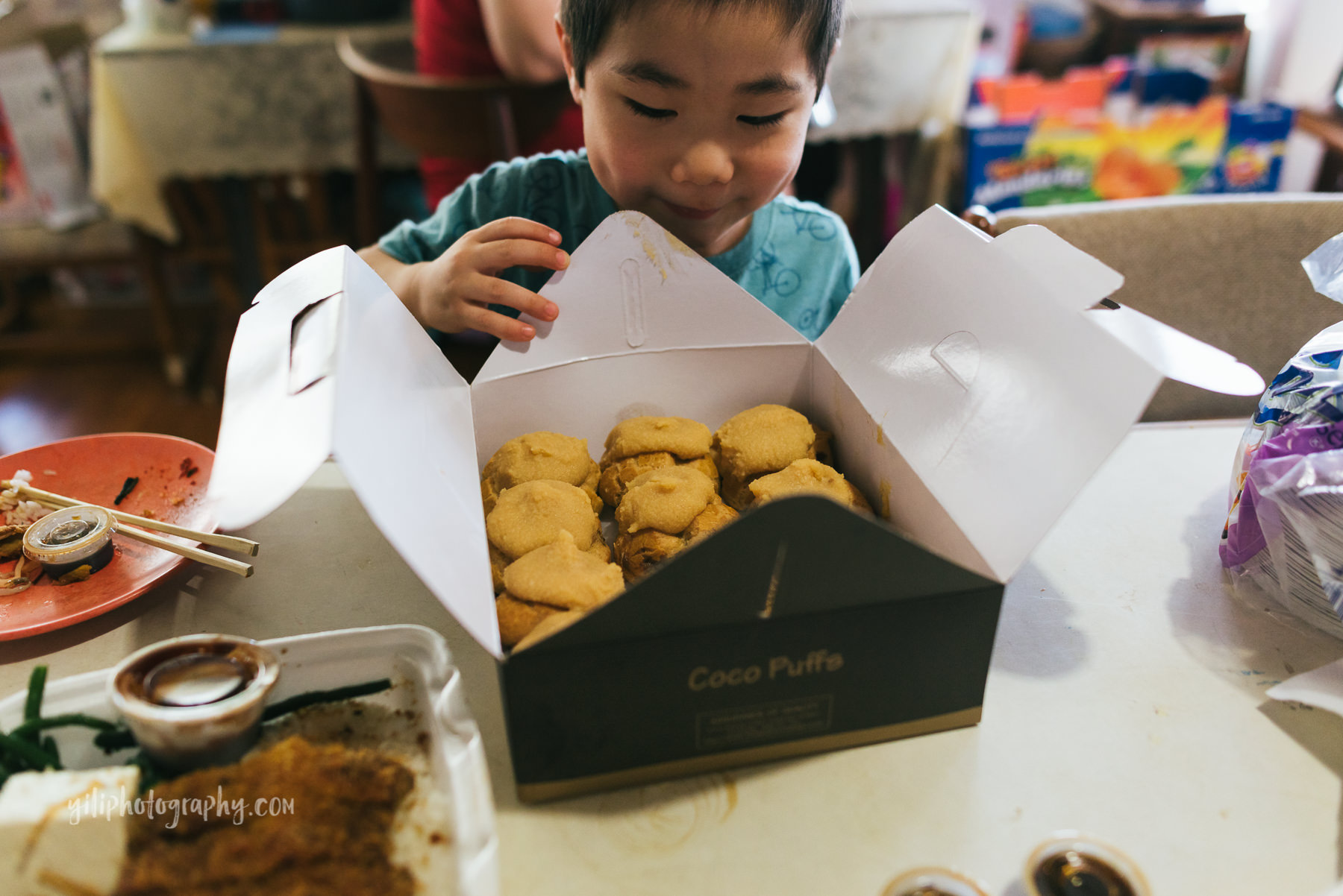 boy looking into box of cream puffs