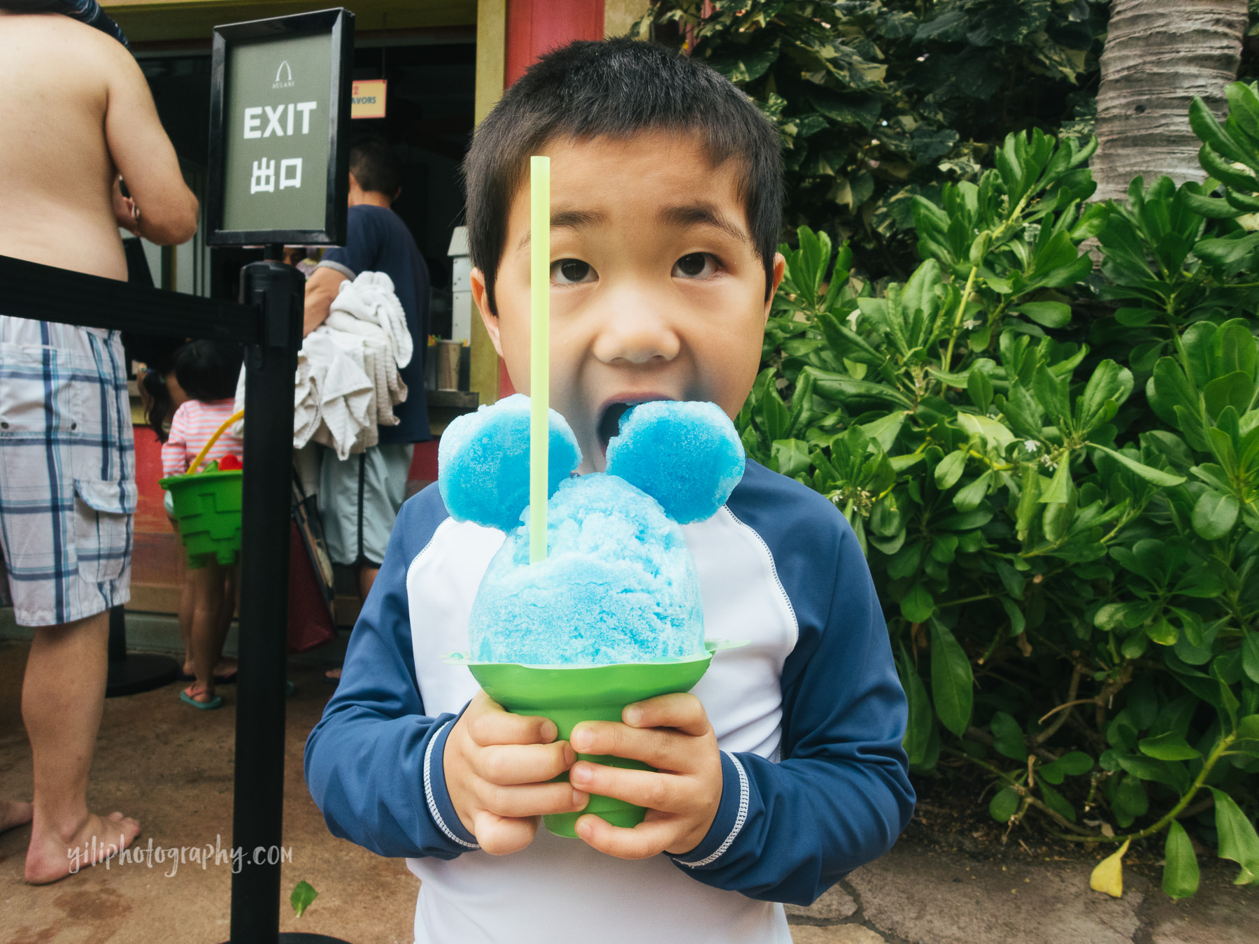 boy biting shave ice with mickey ears
