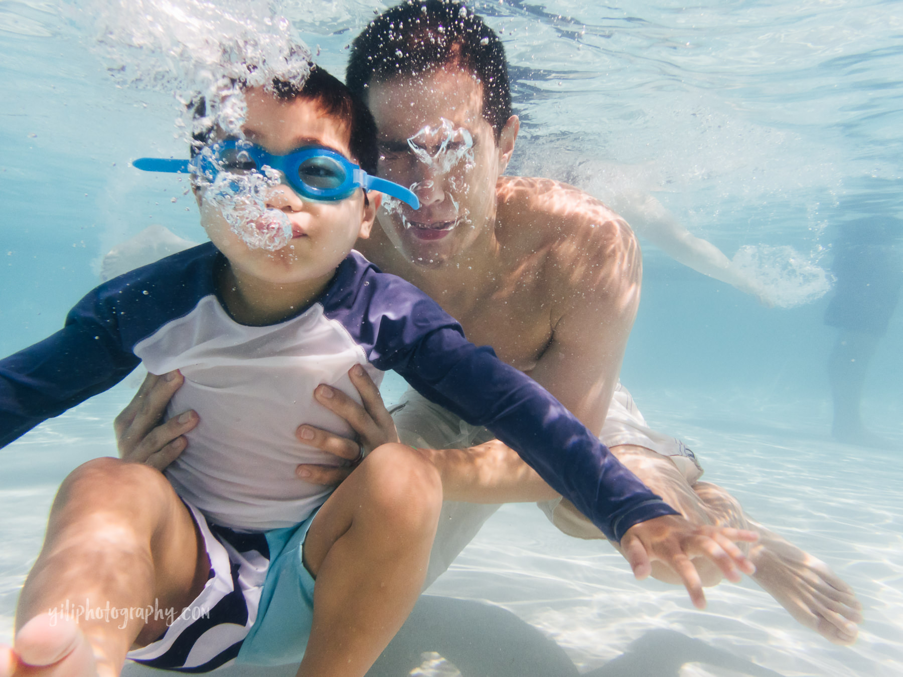 father and son underwater blowing bubbles