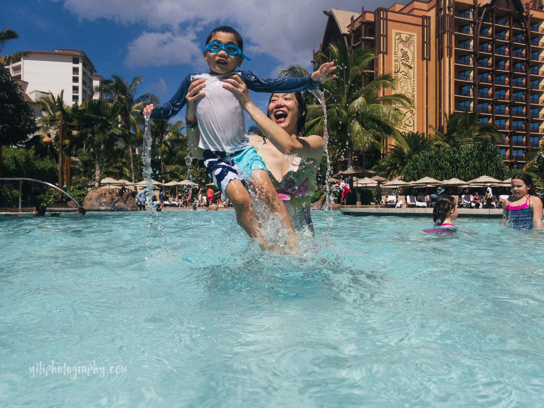 mom splashing with son in pool