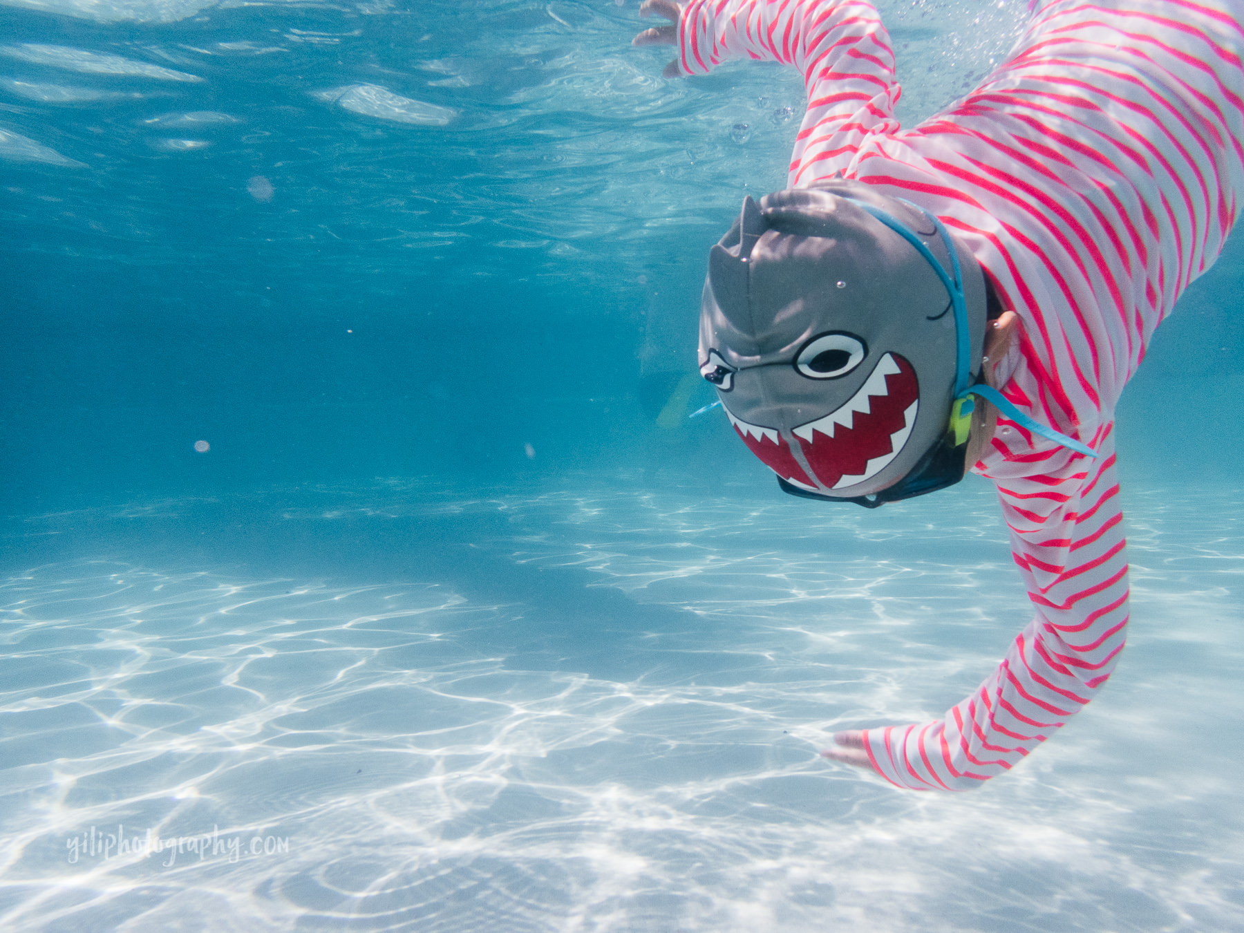 underwater girl diving to touch bottom of pool