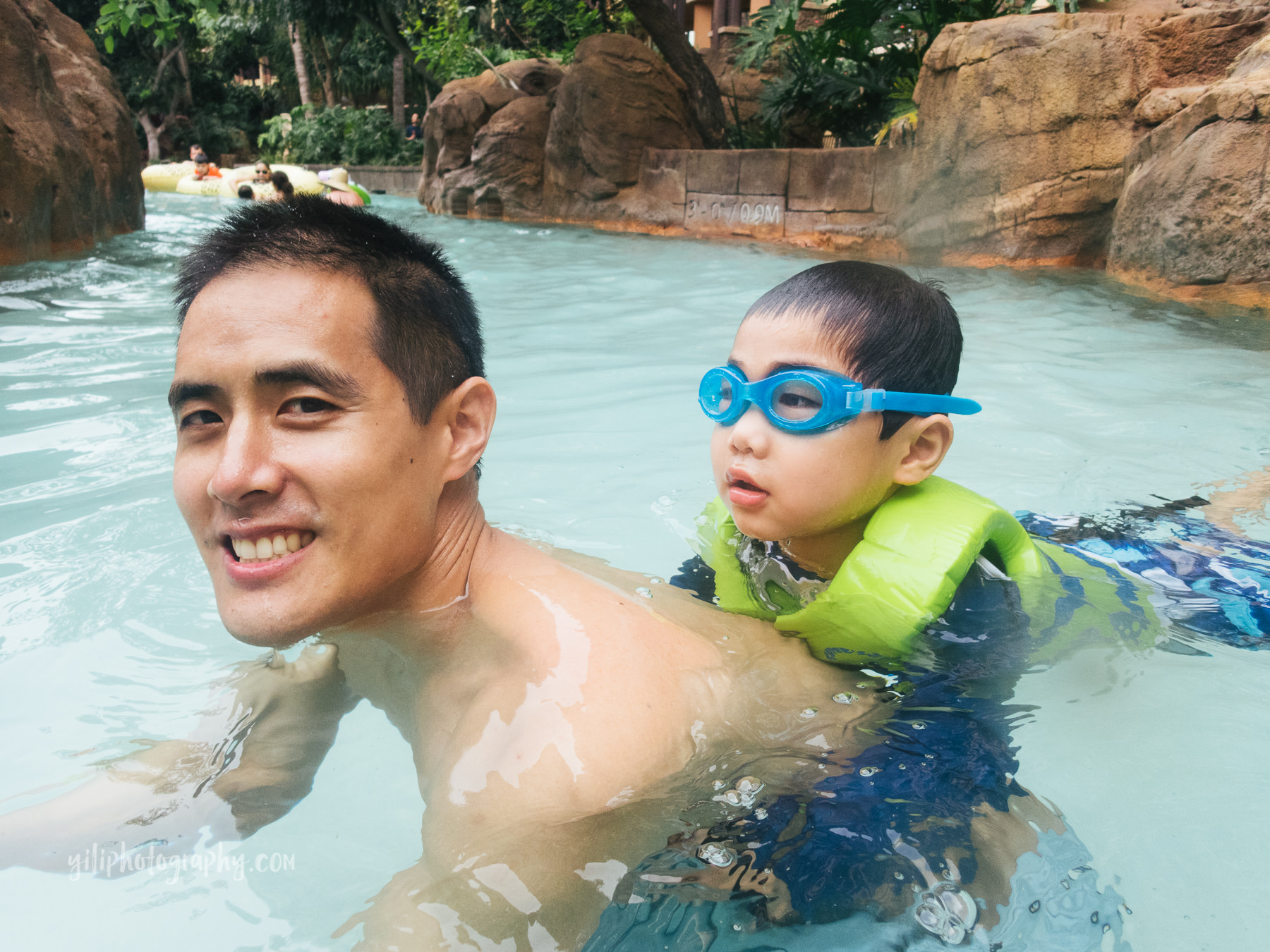 father in pool with son in life jacket