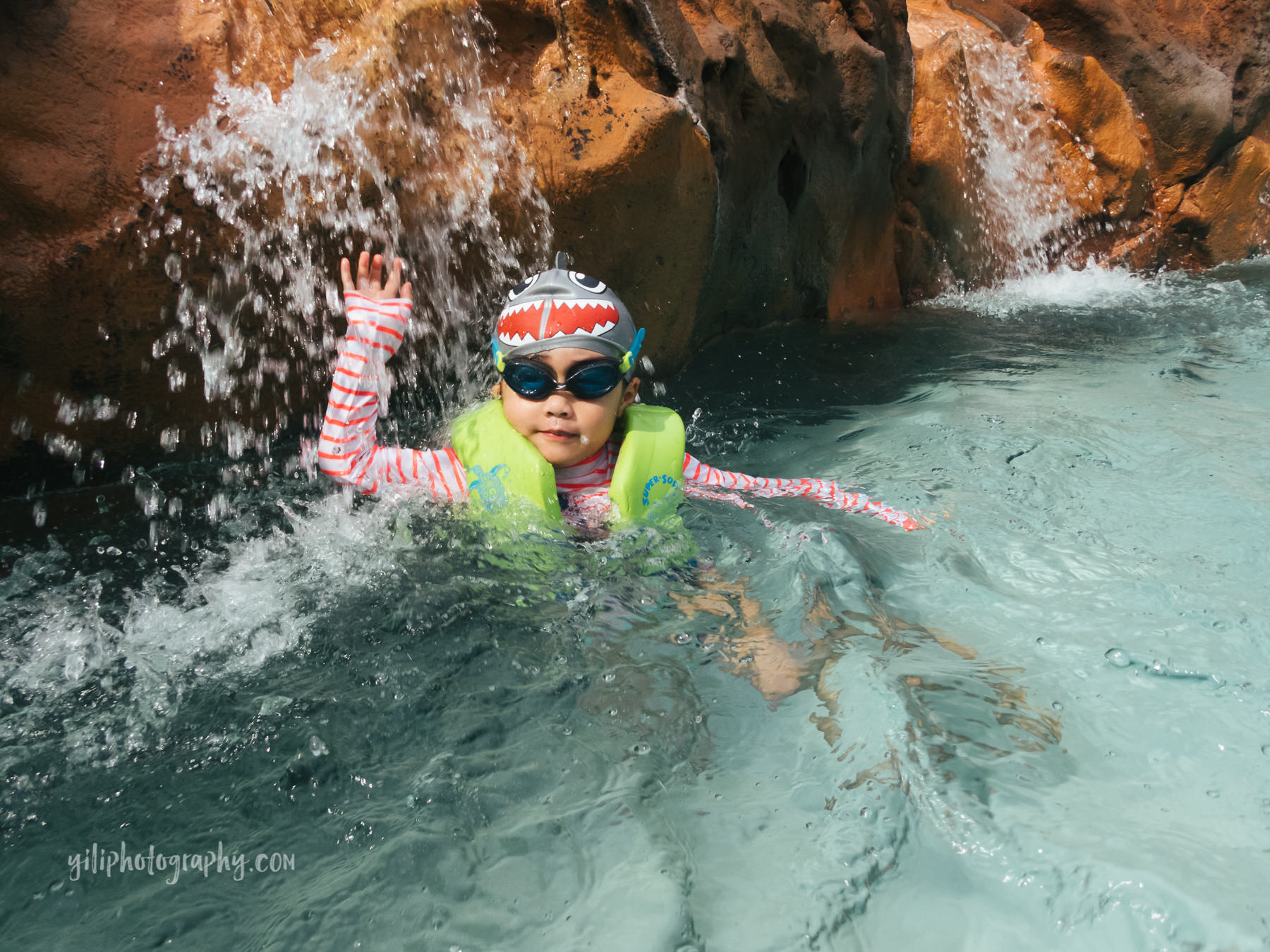 little girl under waterfall in pool