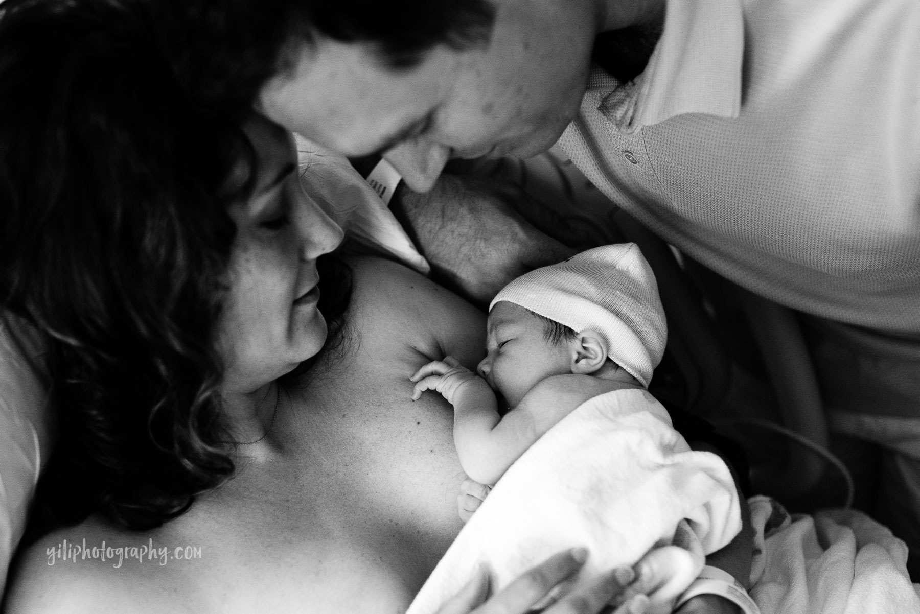 mom and dad admiring newborn baby in hospital room