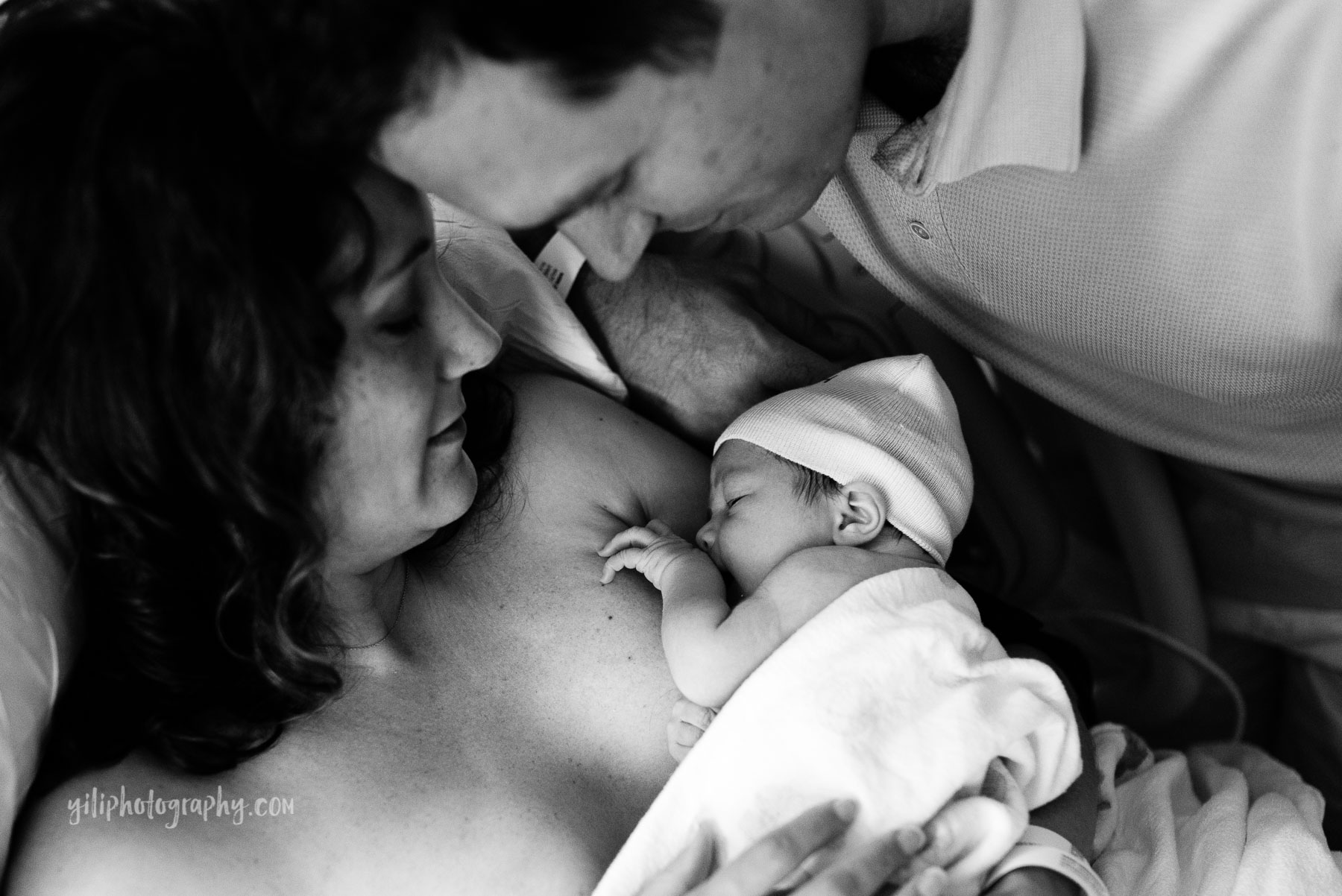 mom and dad admiring newborn baby in hospital room