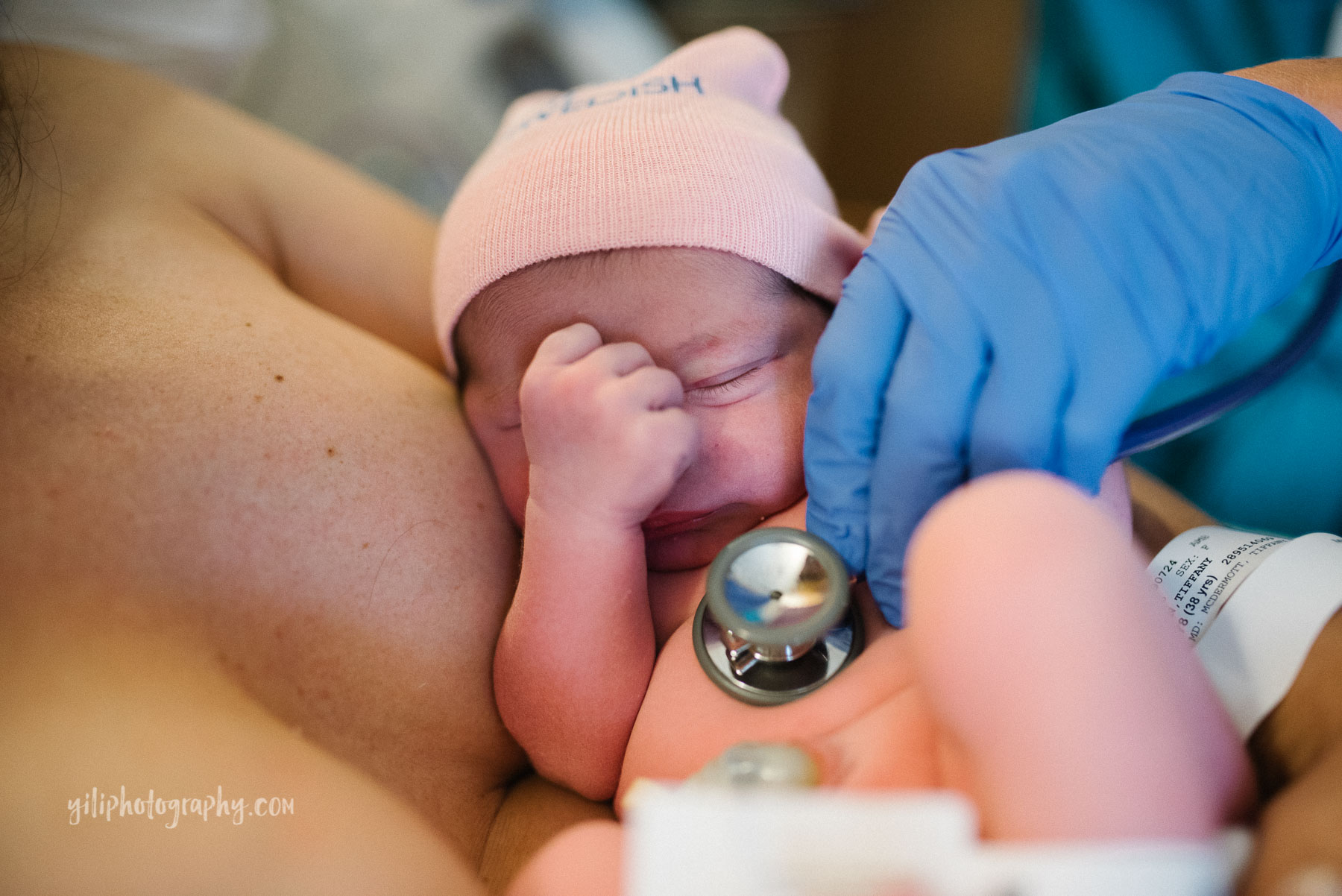 newborn baby on mom's chest being examined with stethescope