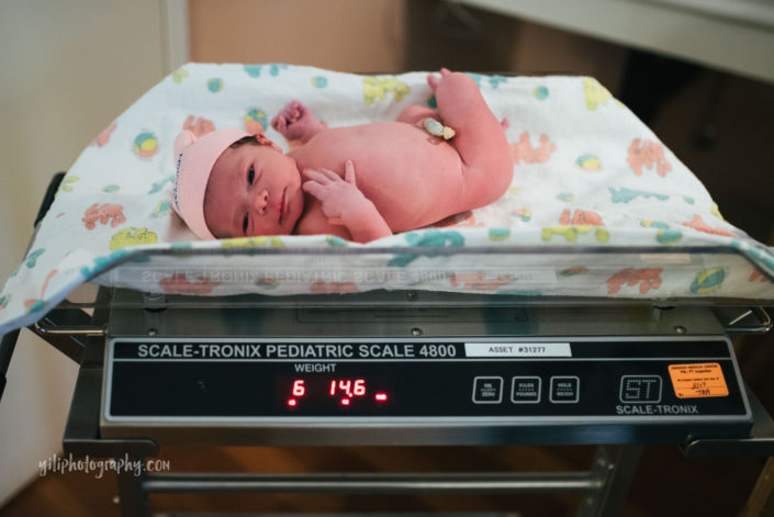 newborn baby girl being weighed on hospital scale