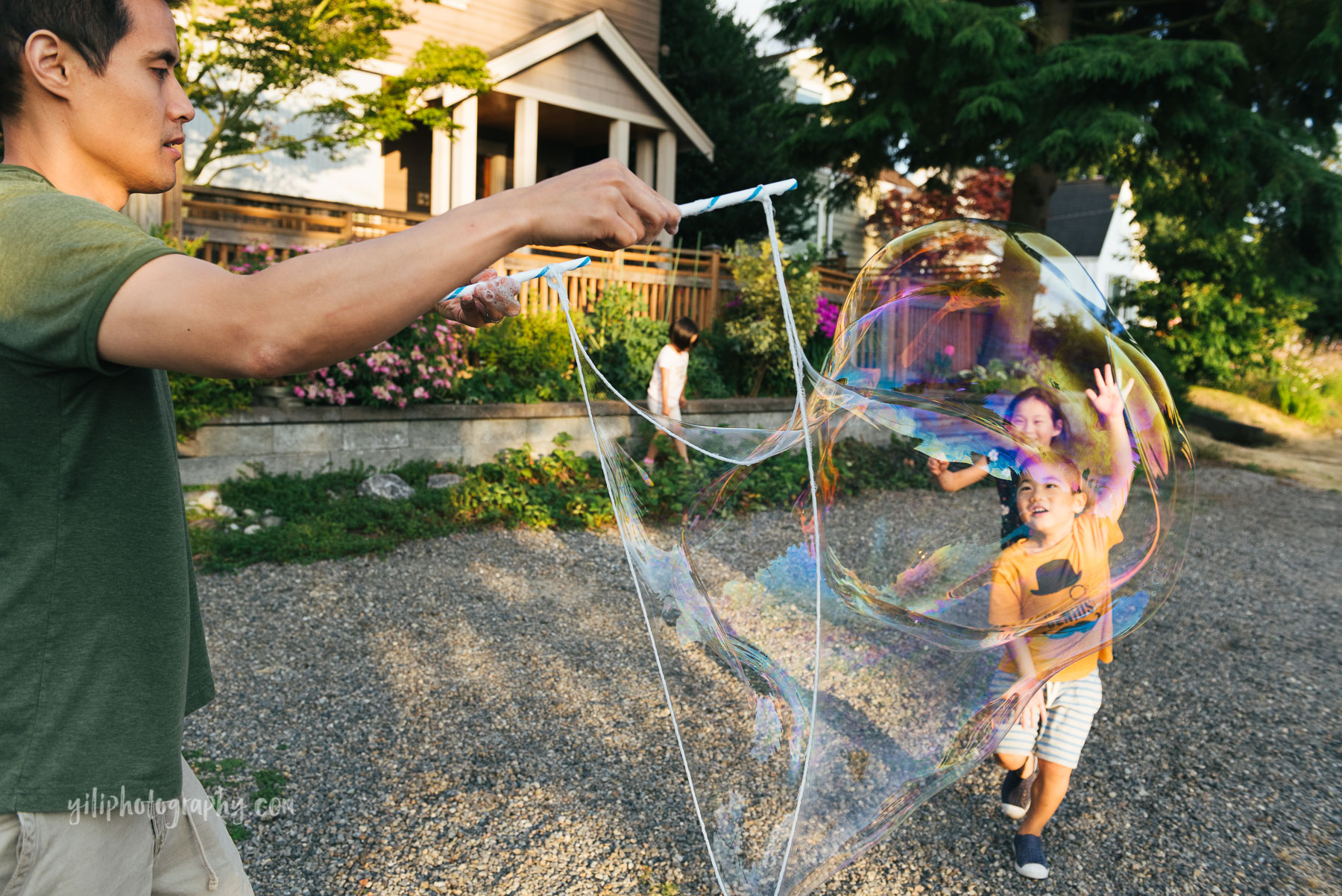 two asian american children running towards giant bubble