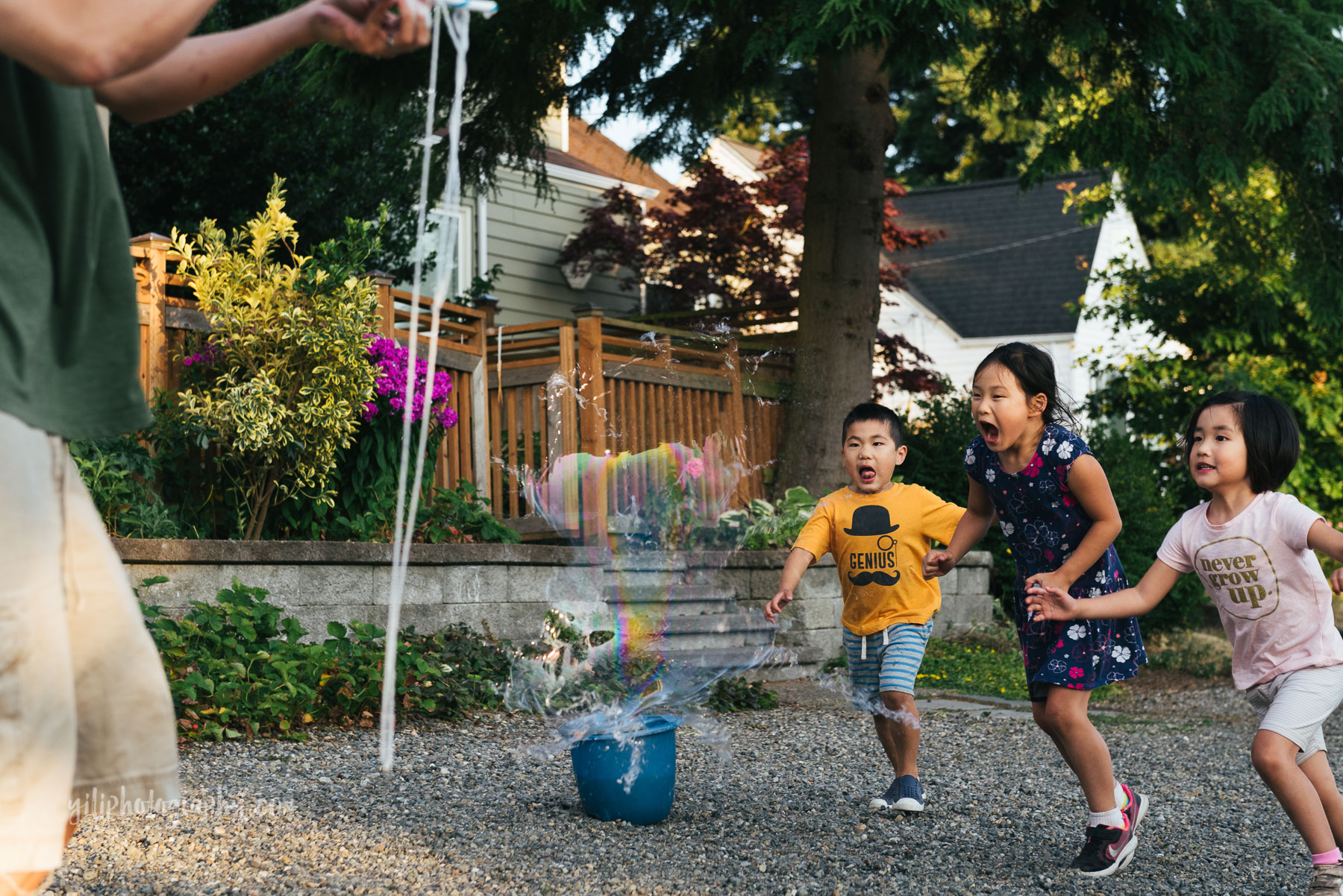 three asian american siblings running towards popping giant bubble