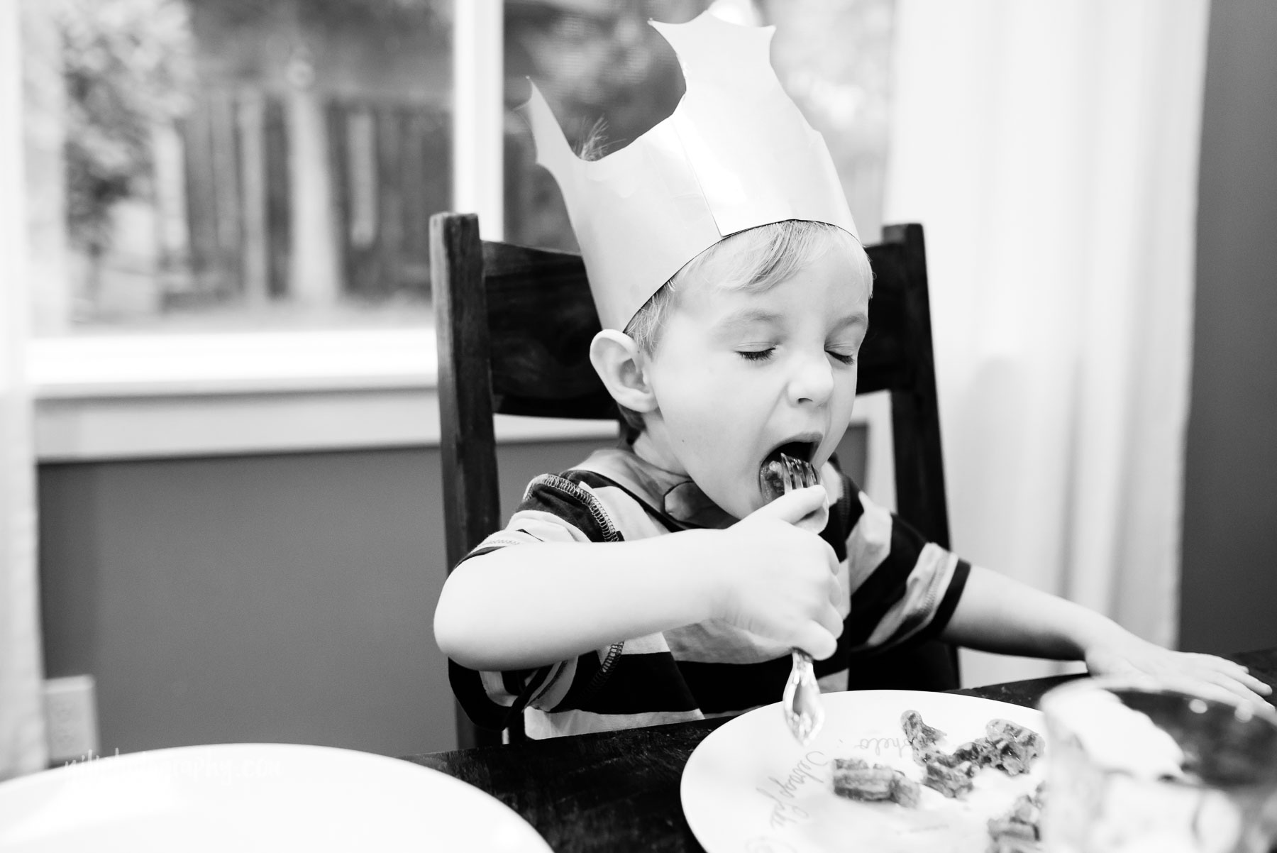 Toddler boy eating waffles while wearing crown
