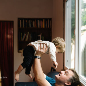 Dad lifting baby girl in air at home