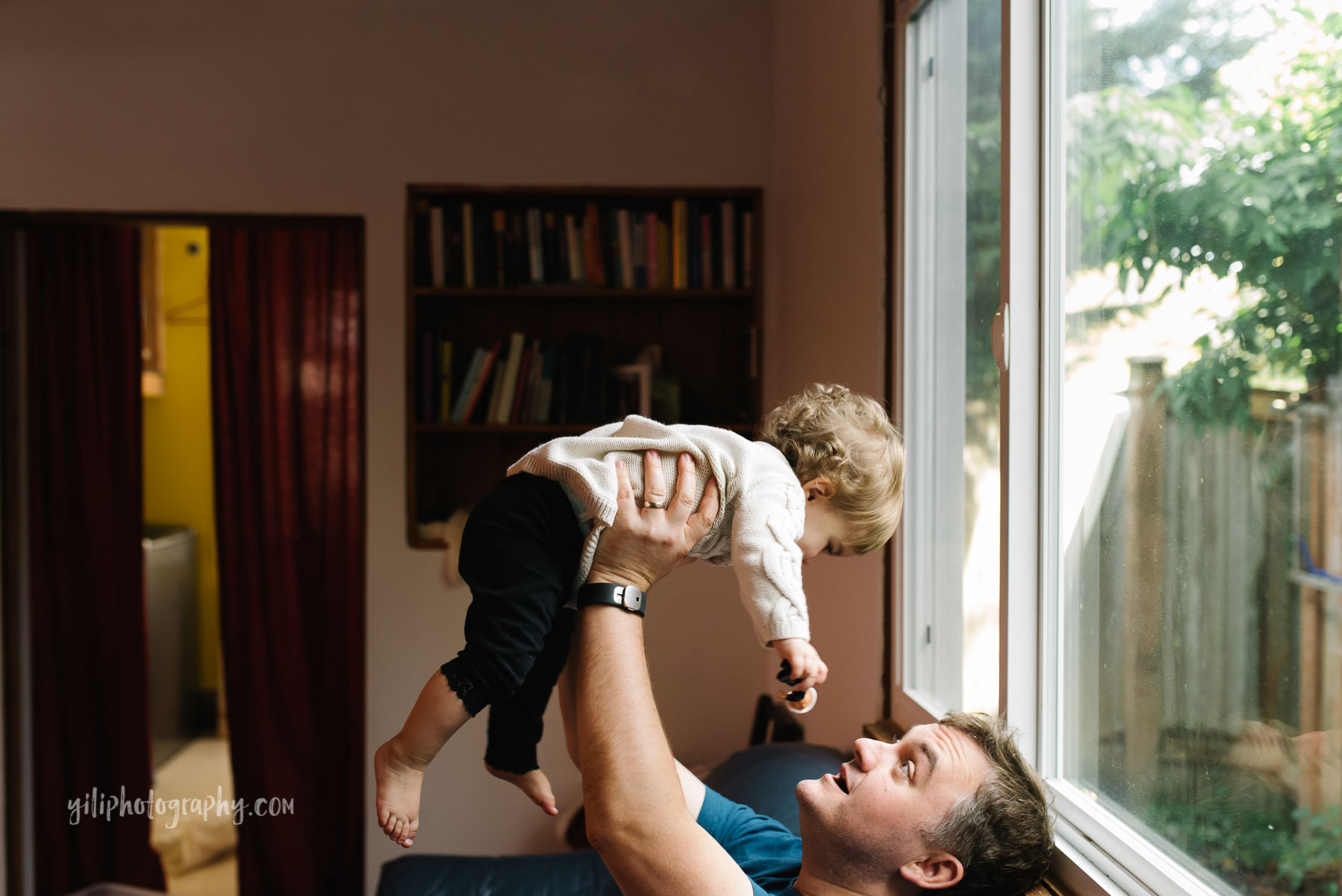Dad lifting baby girl in air at home