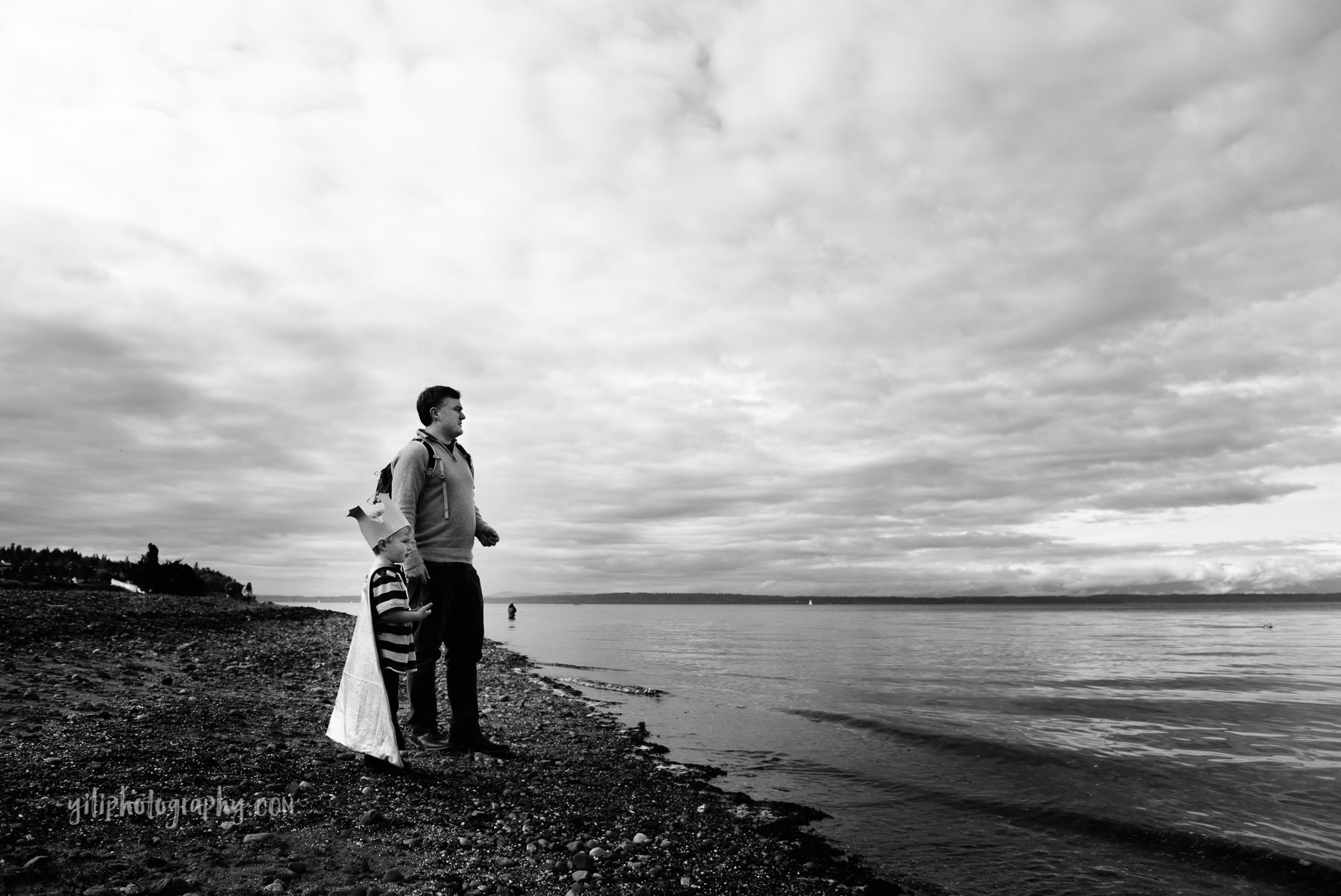 Father and son gazing out at ocean with dramatic clouds