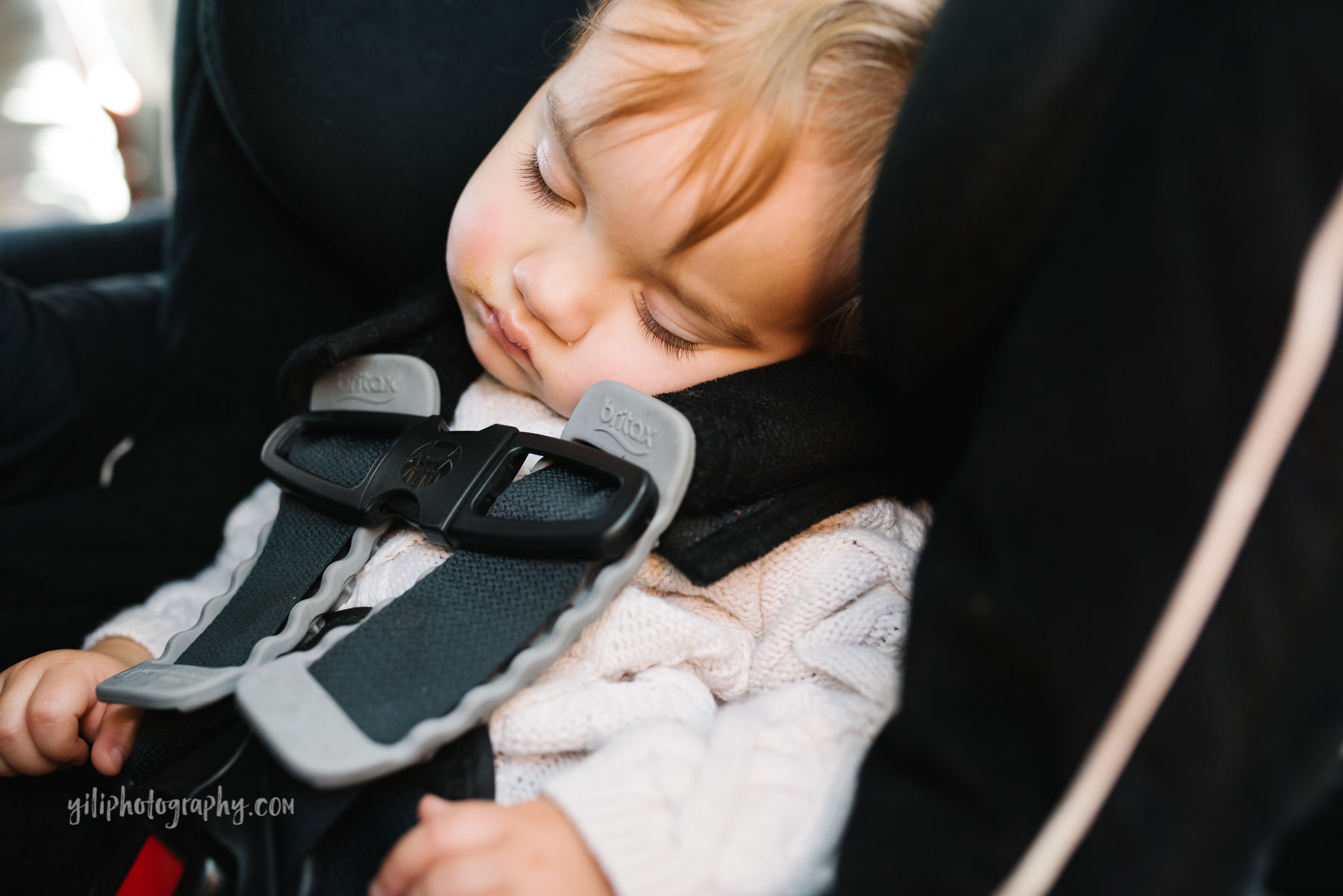 Toddler girl with long eyelashes asleep in carseat