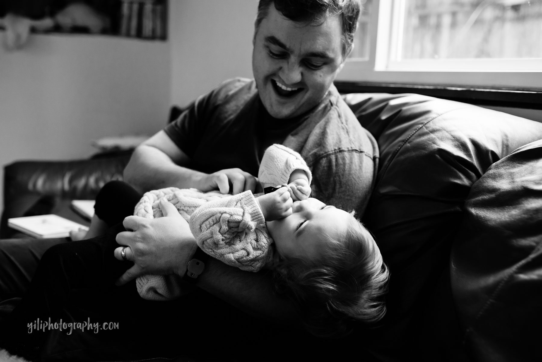 Dad tickling toddler daughter on couch