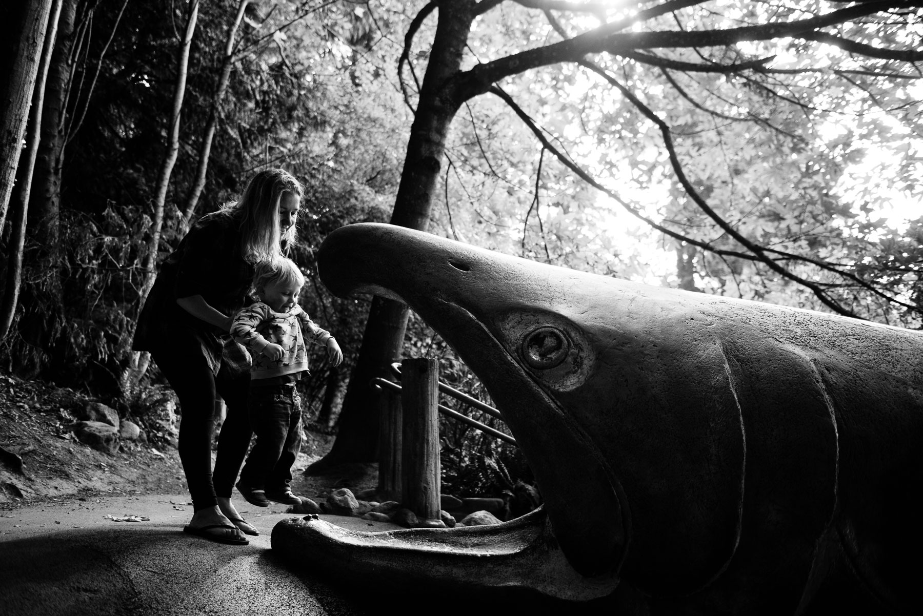 Mother helping toddler son into salmon slide at Carkeek Park Seattle