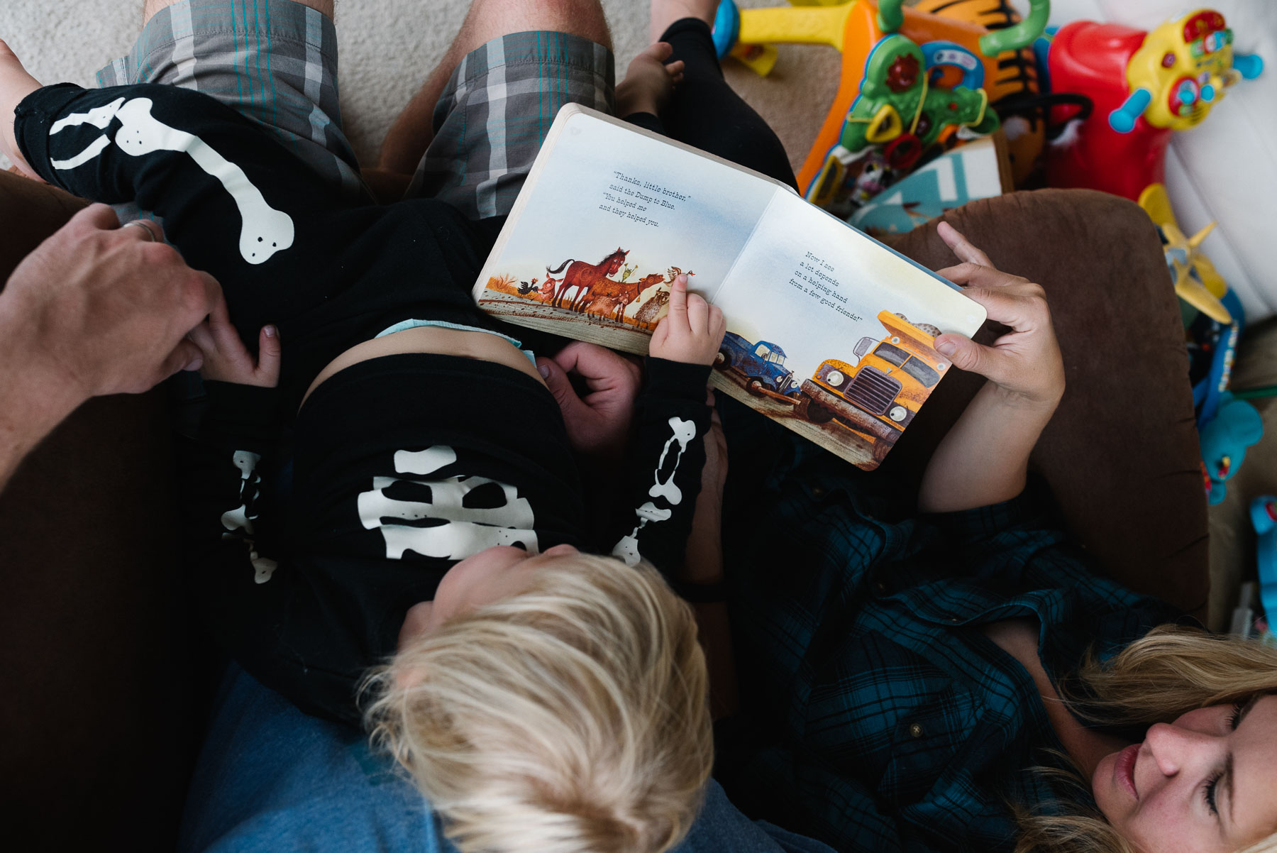 Top down view of parents reading Little Blue Truck to toddler son