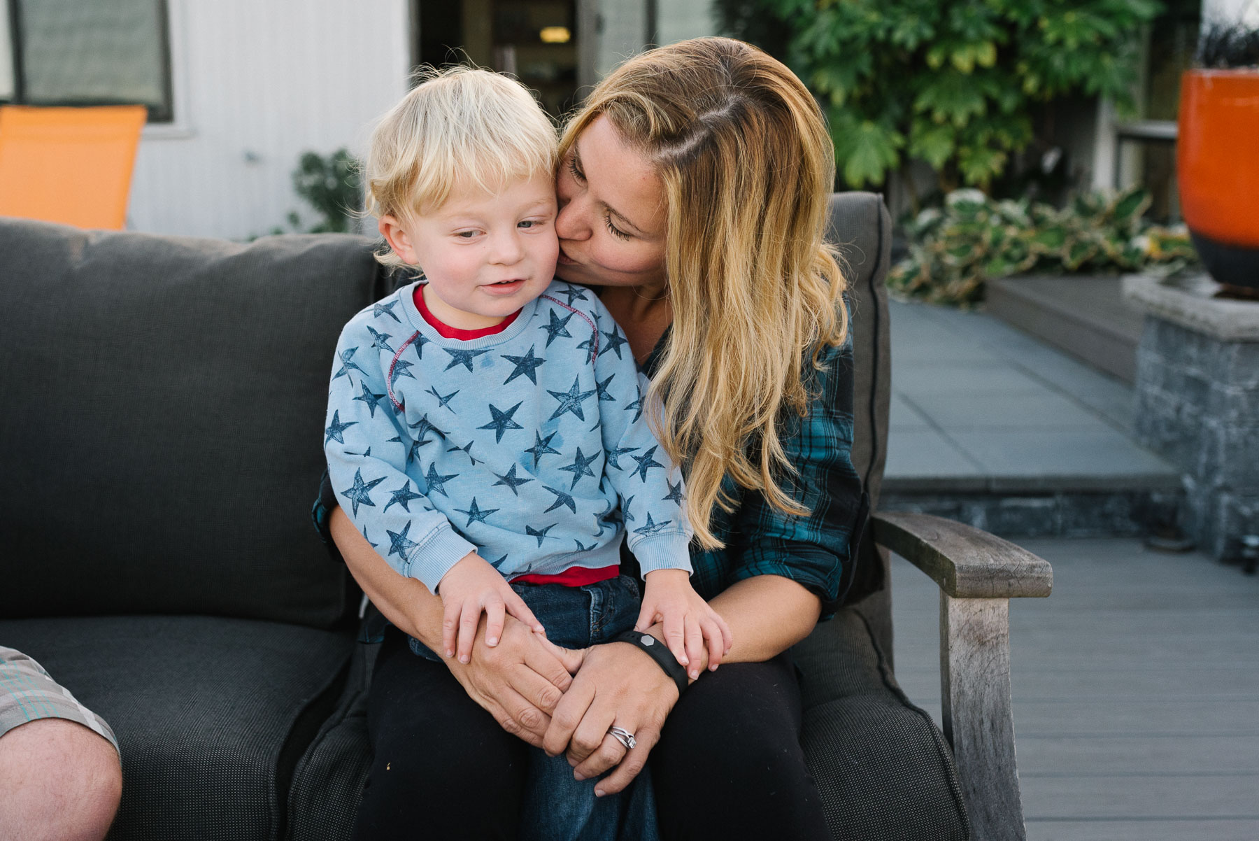Toddler boy sitting on mom's lap while she kisses his cheek