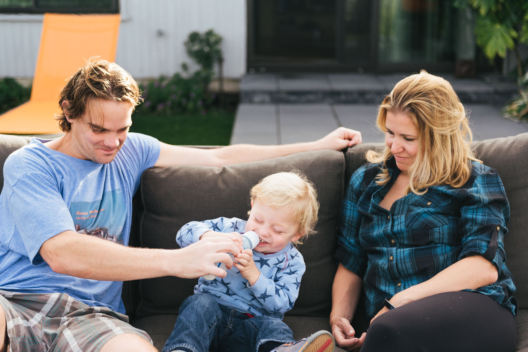 Family sitting on patio furniture outdoors acting silly