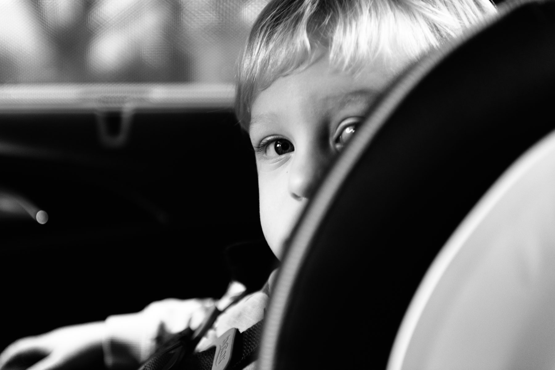 Toddler boy peeking over side of carseat