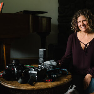 Female photographer sitting in living room with camera equipment on coffee table