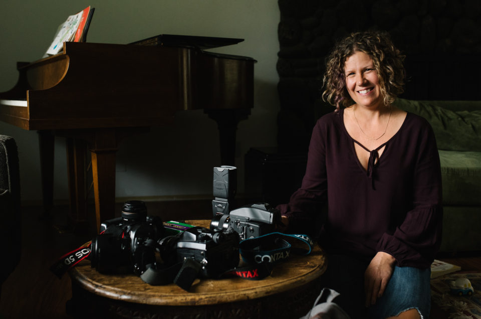 Female photographer sitting in living room with camera equipment on coffee table