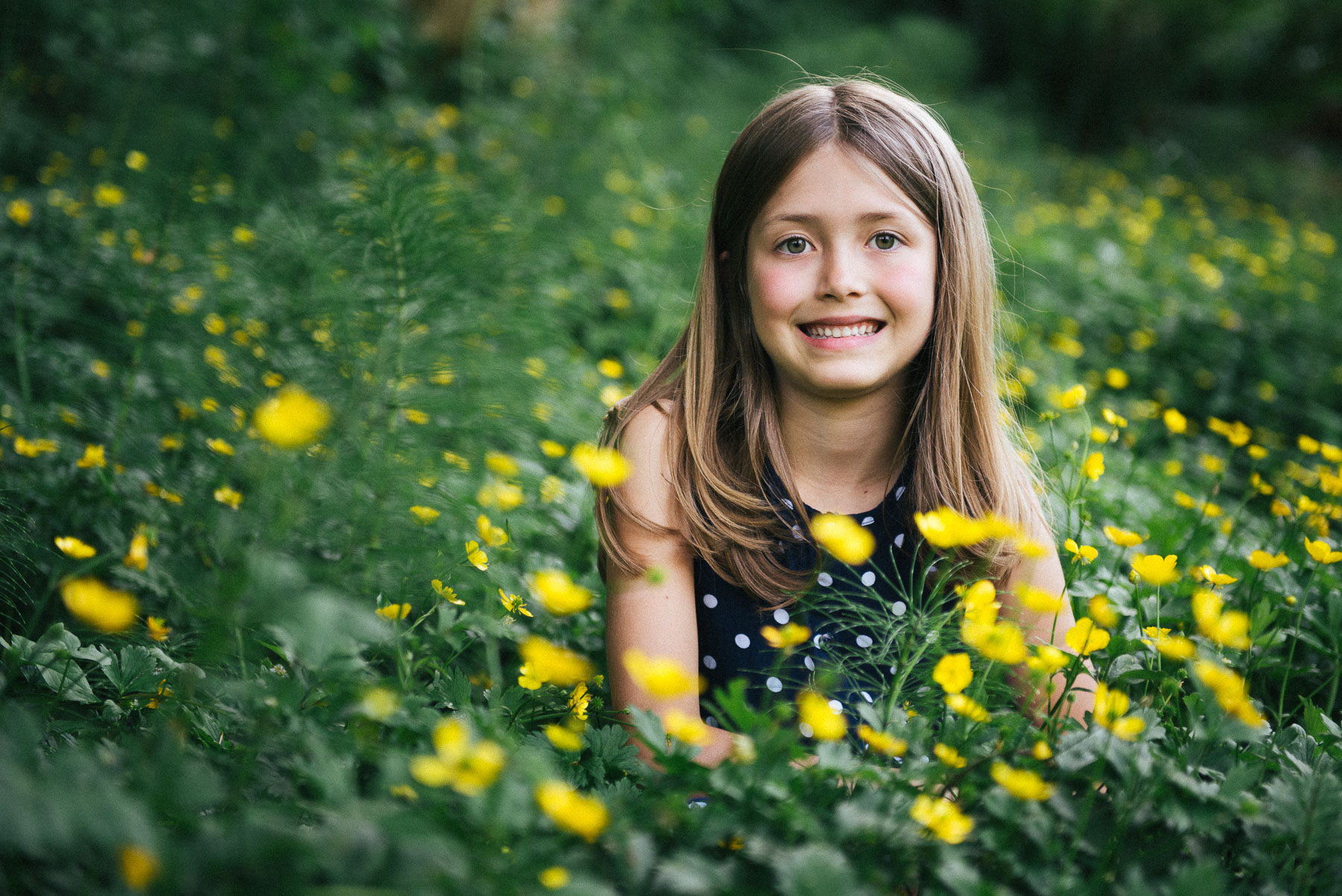 Caucasian young girl smiling among green plants with yellow flowers