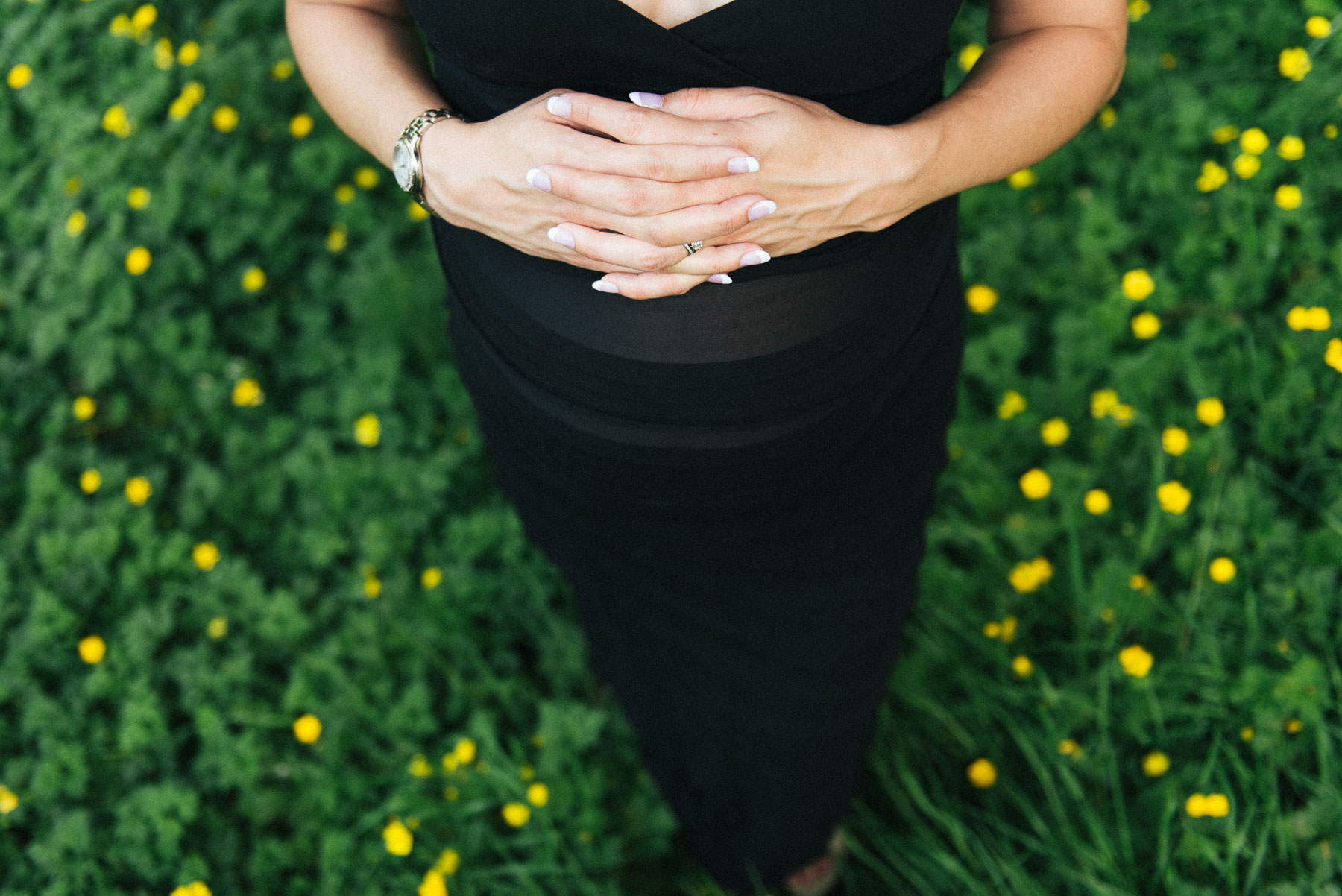 Top down photo of expecting mother's belly with hands clasped on belly