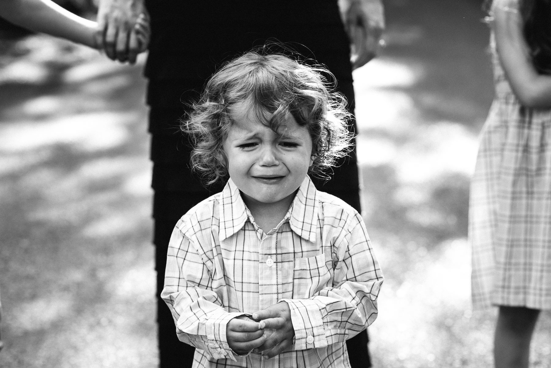 Toddler boy with curly hair crying outside