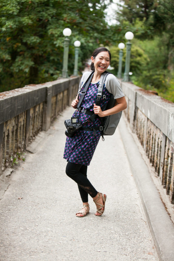 Asian female photographer posing and smiling with gear