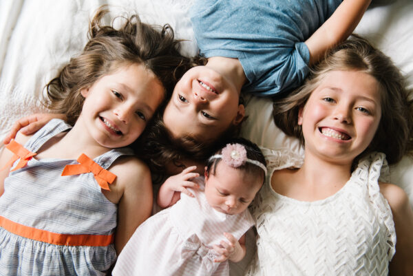 top down photo of four siblings on bed smiling
