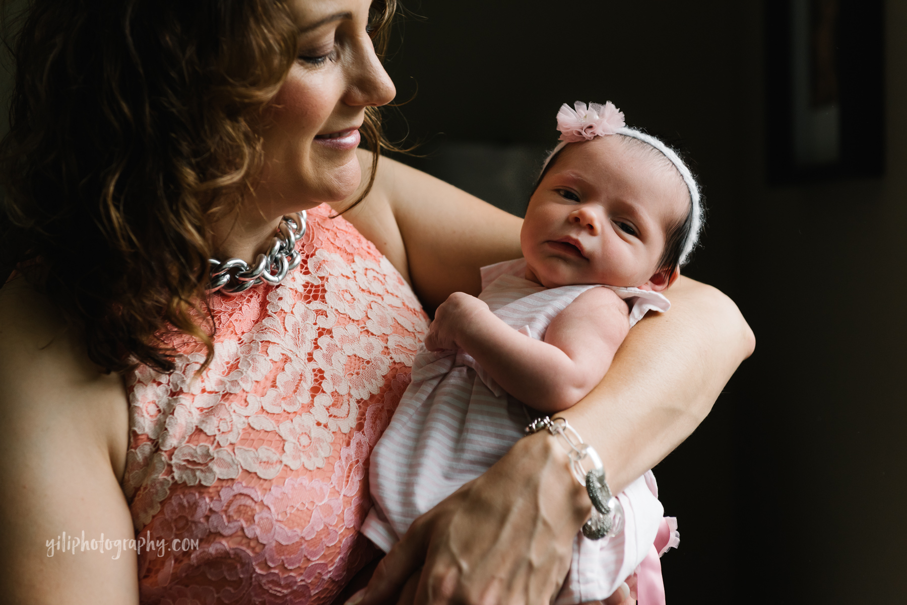 mother smiling while looking at newborn baby girl in her arms