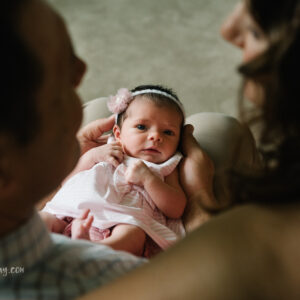 top down photo of newborn baby girl looking up at parents while they look at her